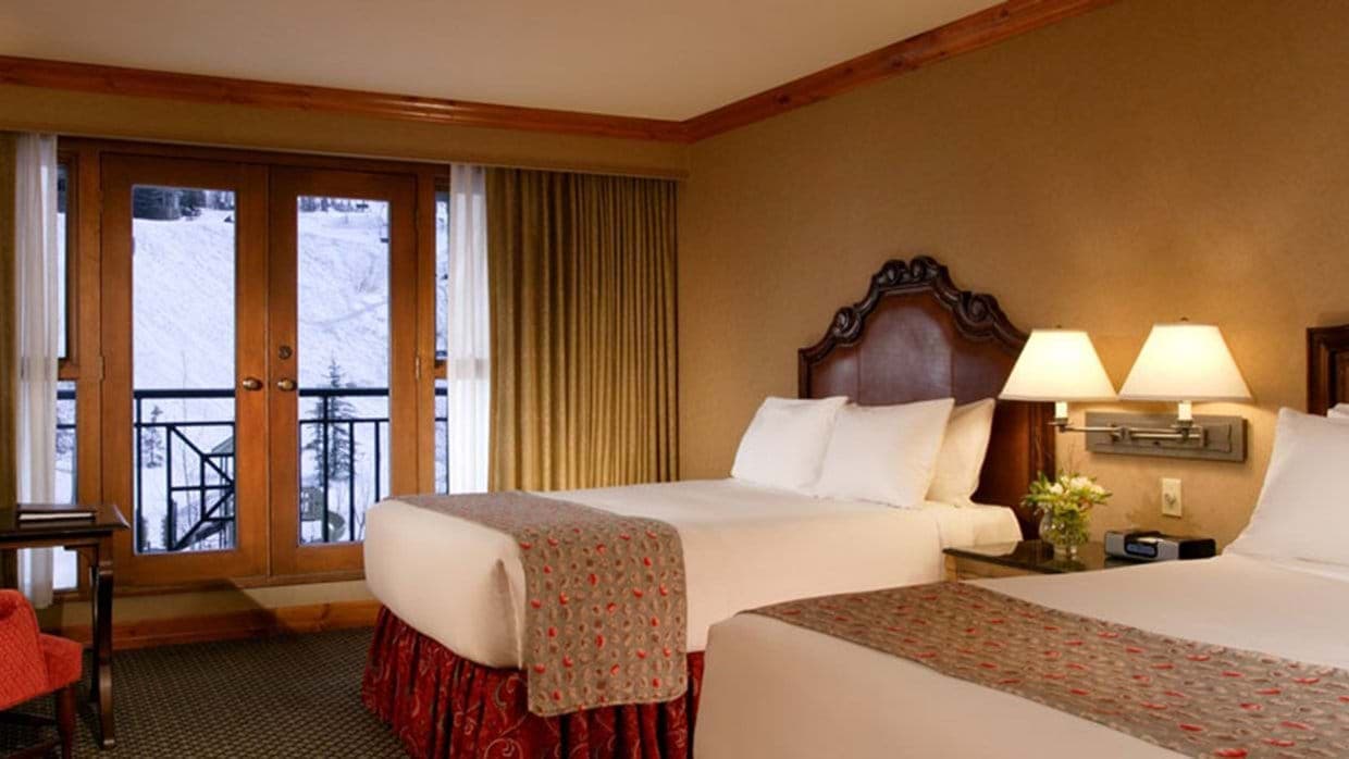 Guest bedroom with two queen beds and private balcony with ski-in access view