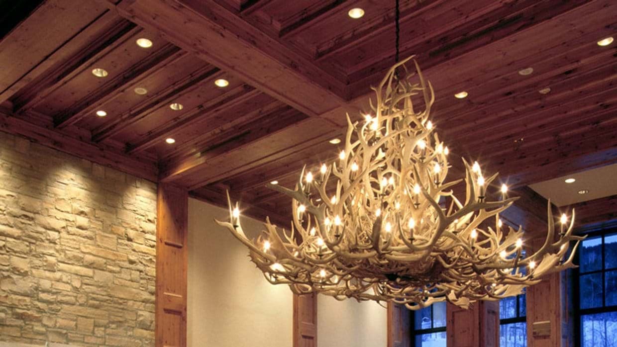 Great room featuring antler chandelier, coffered wood ceilings, and stone masonry