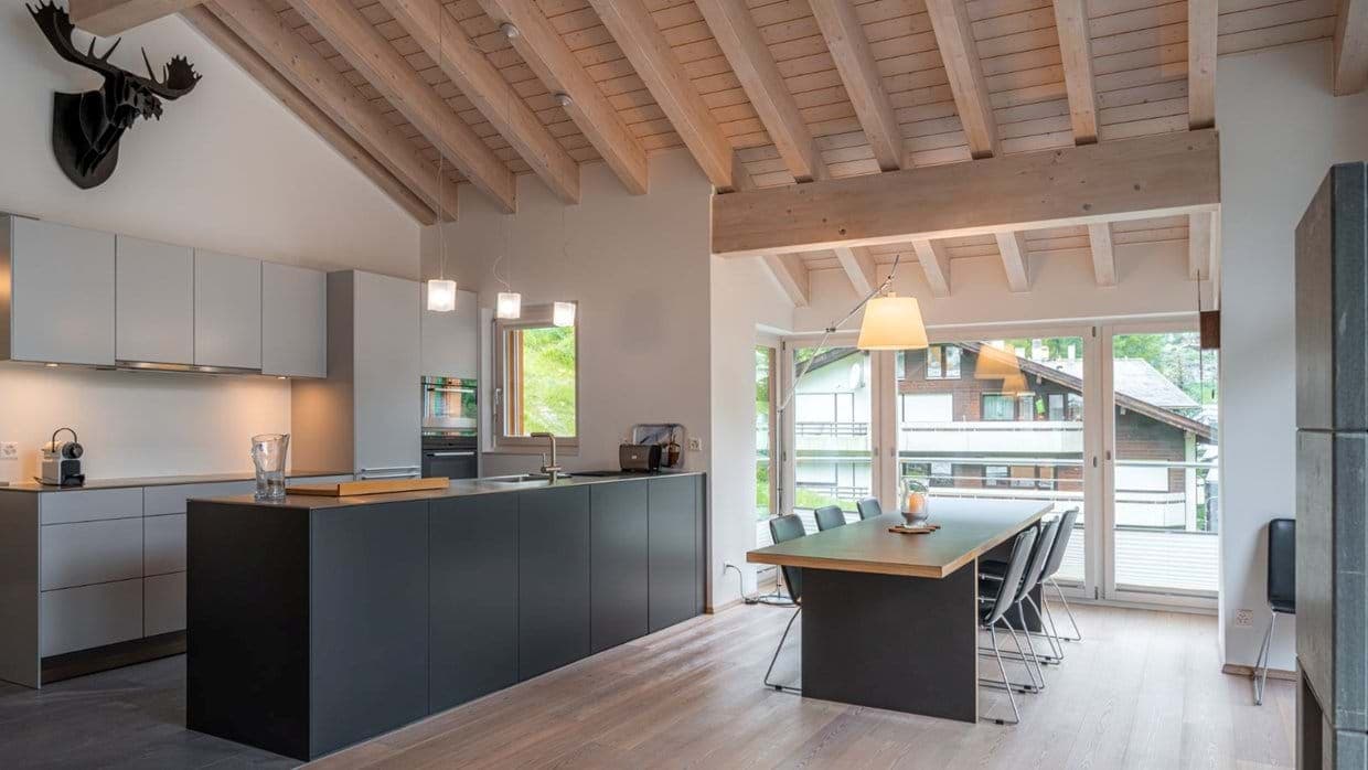 Open-plan kitchen and dining area with vaulted beam ceilings and seating for 8