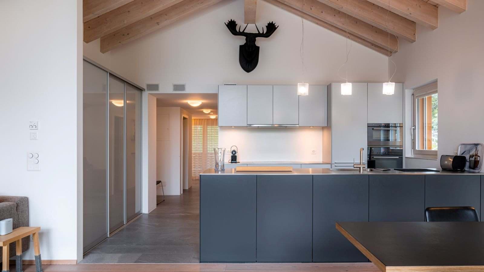 Kitchen with island sink, dual wall ovens, and vaulted wood-beam ceiling