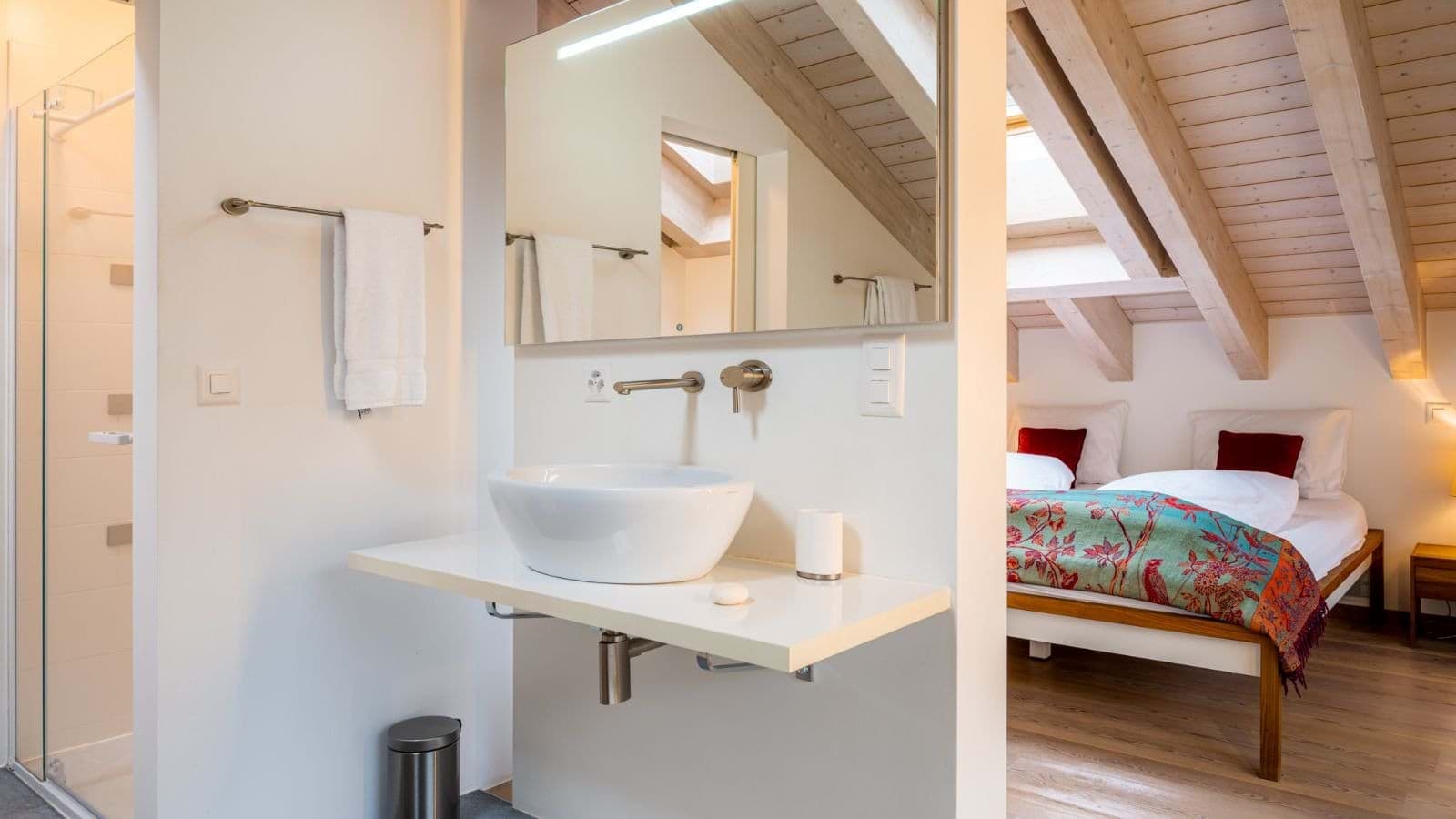 Ensuite bathroom with walk-in shower and vessel sink adjacent to twin bedroom