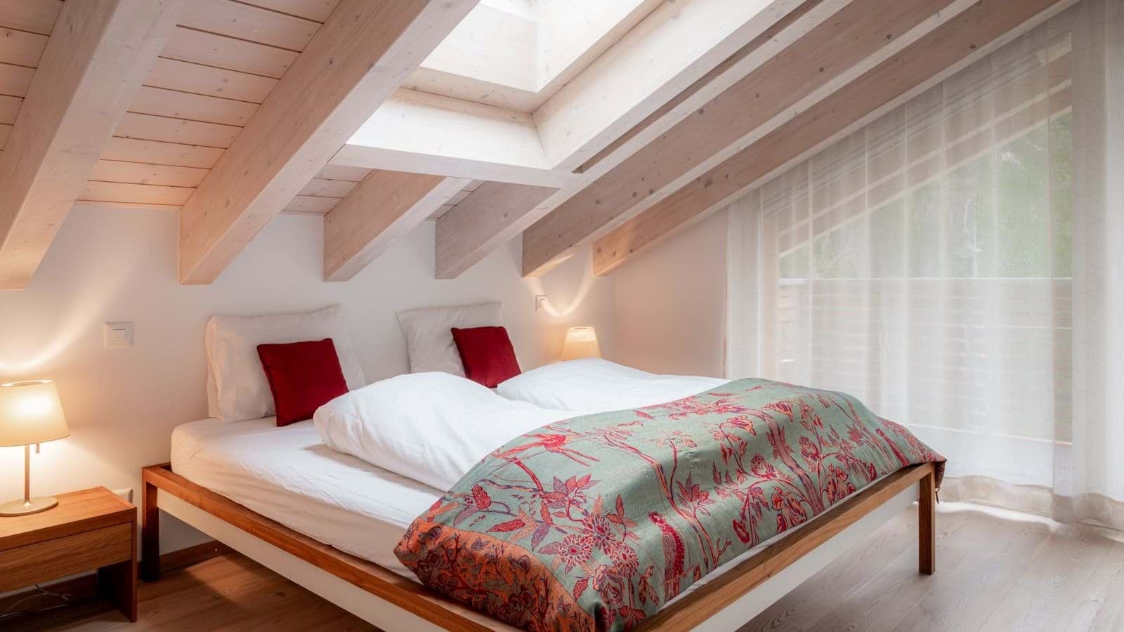 Attic bedroom with queen bed and skylight over exposed timber beams