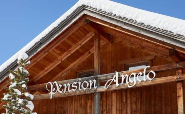 Timber facade of Pension Angelo lodge with snow-covered roof
