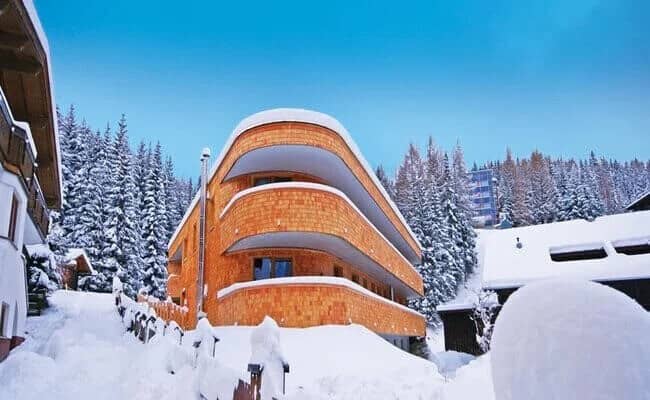 Ski-in exterior with curved timber balconies and forest views