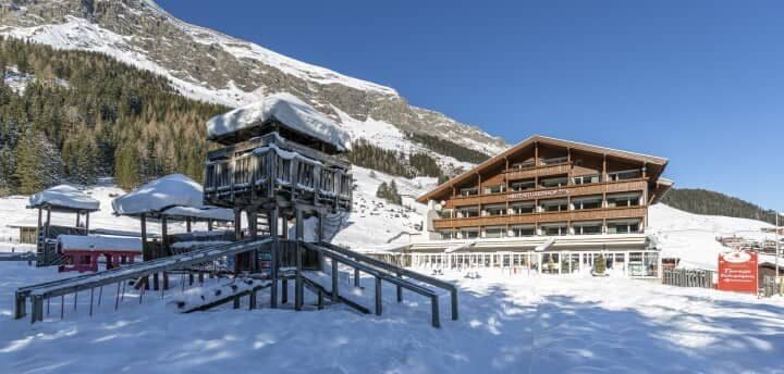 Ski-in/ski-out hotel exterior with on-site wooden playground and mountain views