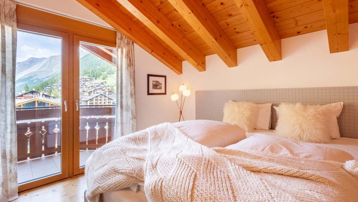 Bedroom with vaulted wood ceilings and private balcony with mountain views