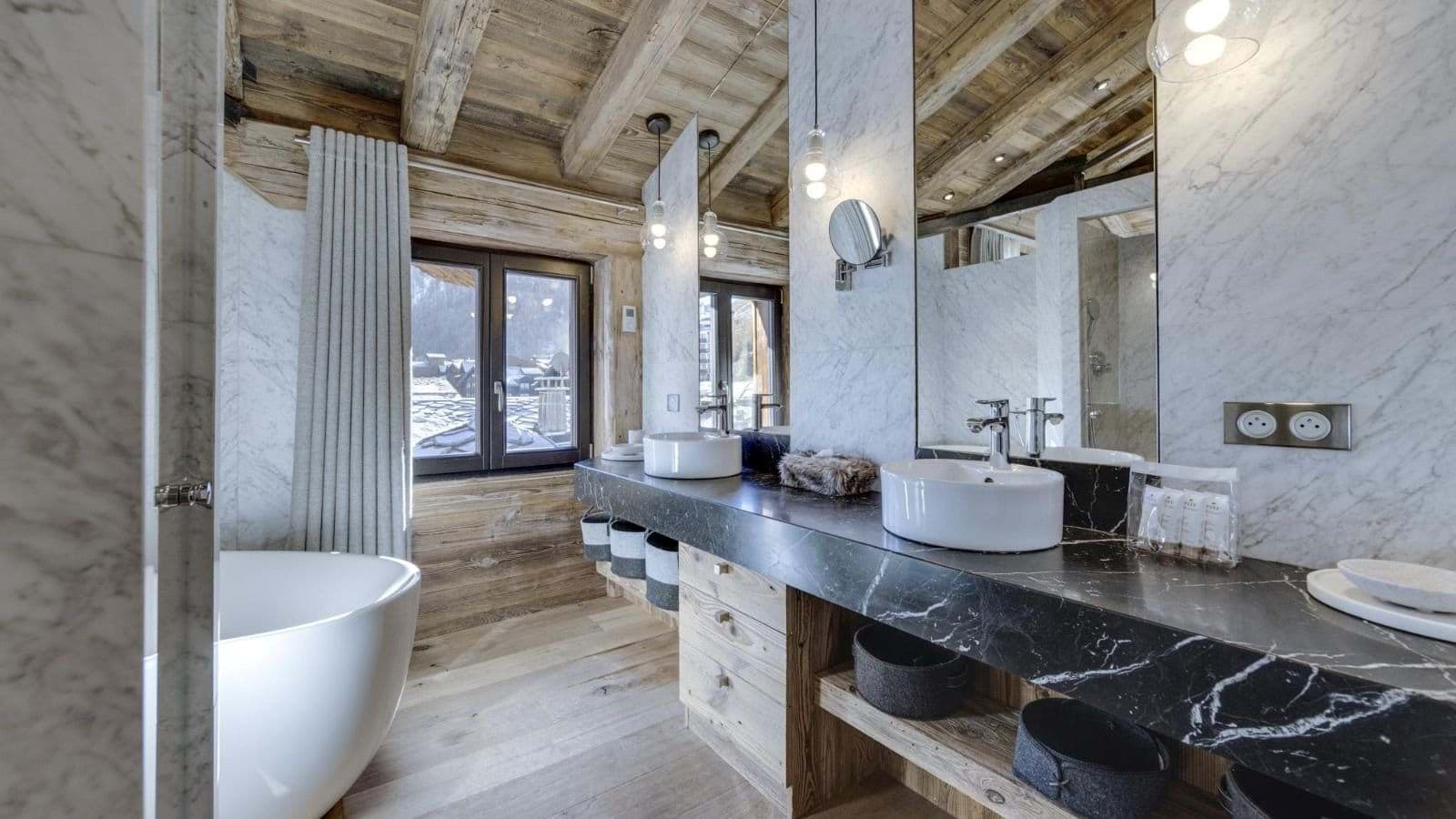 Bathroom with dual vessel sinks, marble walls, and freestanding soaking tub