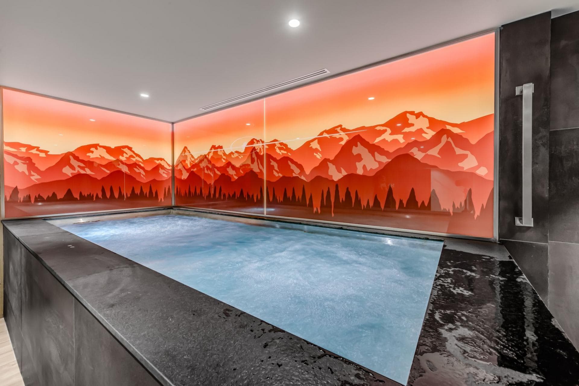Indoor hot tub with backlit mountain mural and grab rail