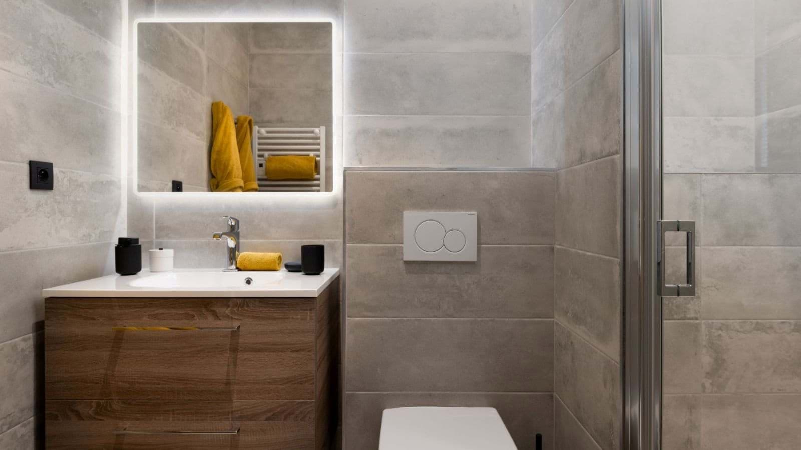 Bathroom with backlit mirror, heated towel rail, and walk-in shower