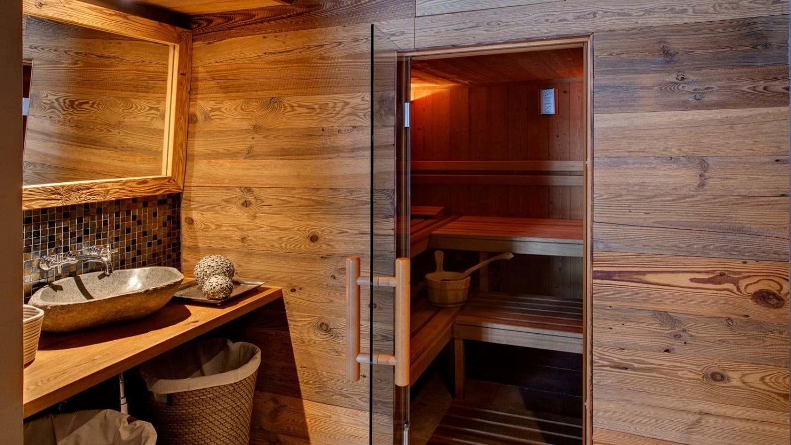 Private cedar sauna with glass door and stone vessel sink