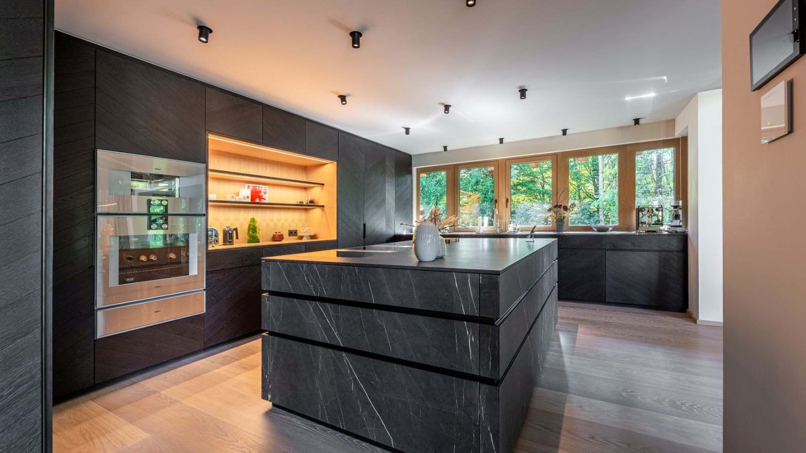 Kitchen with stone island, double wall ovens, and forest views