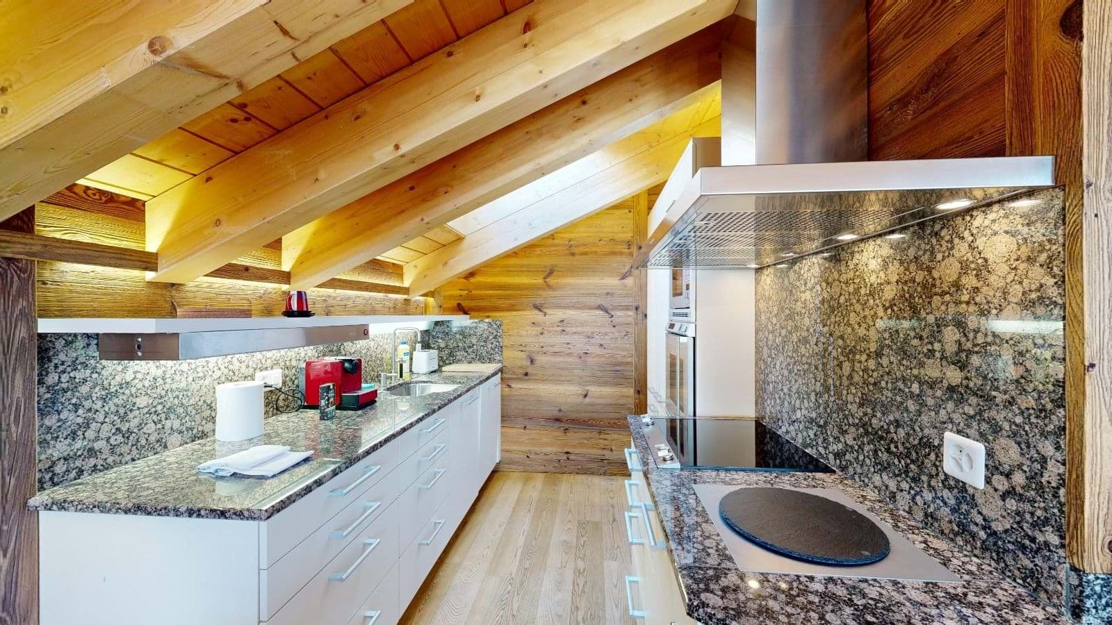 Galley kitchen with granite counters, induction cooktop, and vaulted timber ceilings