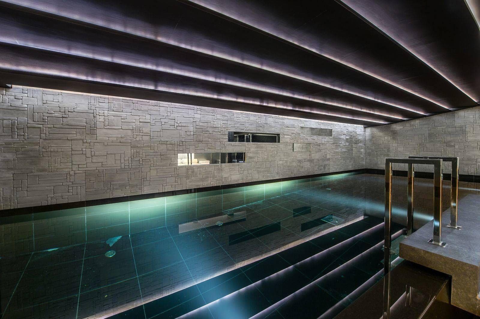 Indoor heated lap pool with stone walls and integrated step entry
