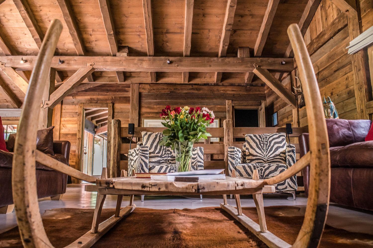 Log cabin living area with exposed timber beams and vintage sled coffee table