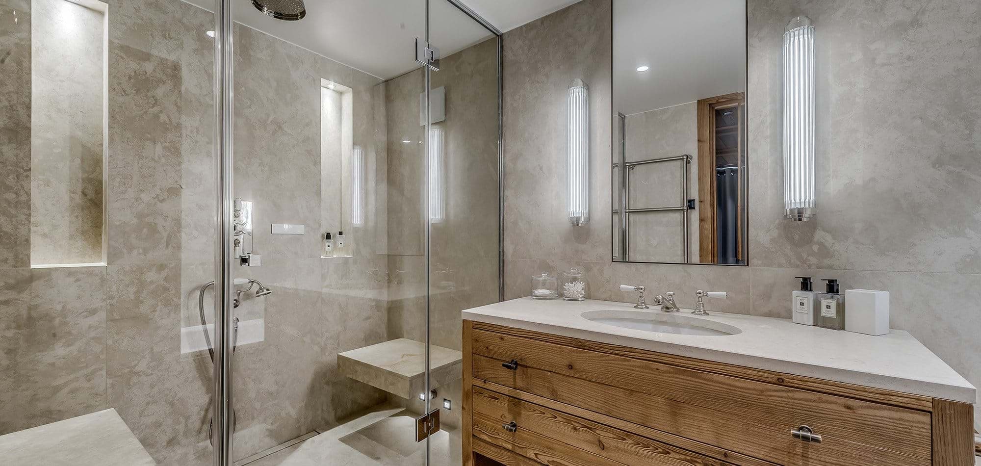 Bathroom featuring walk-in glass shower with built-in stone bench and rainfall head