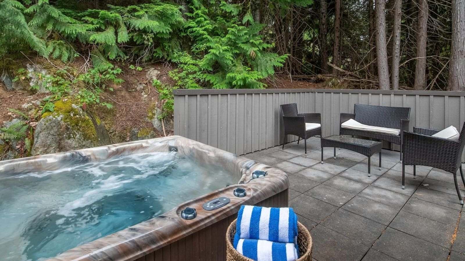 Private patio with 6-person hot tub and forest backdrop
