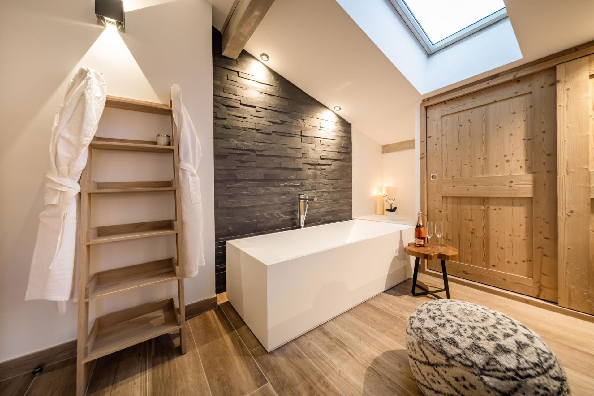 Bathroom with soaking tub, stone accent wall, and overhead skylight