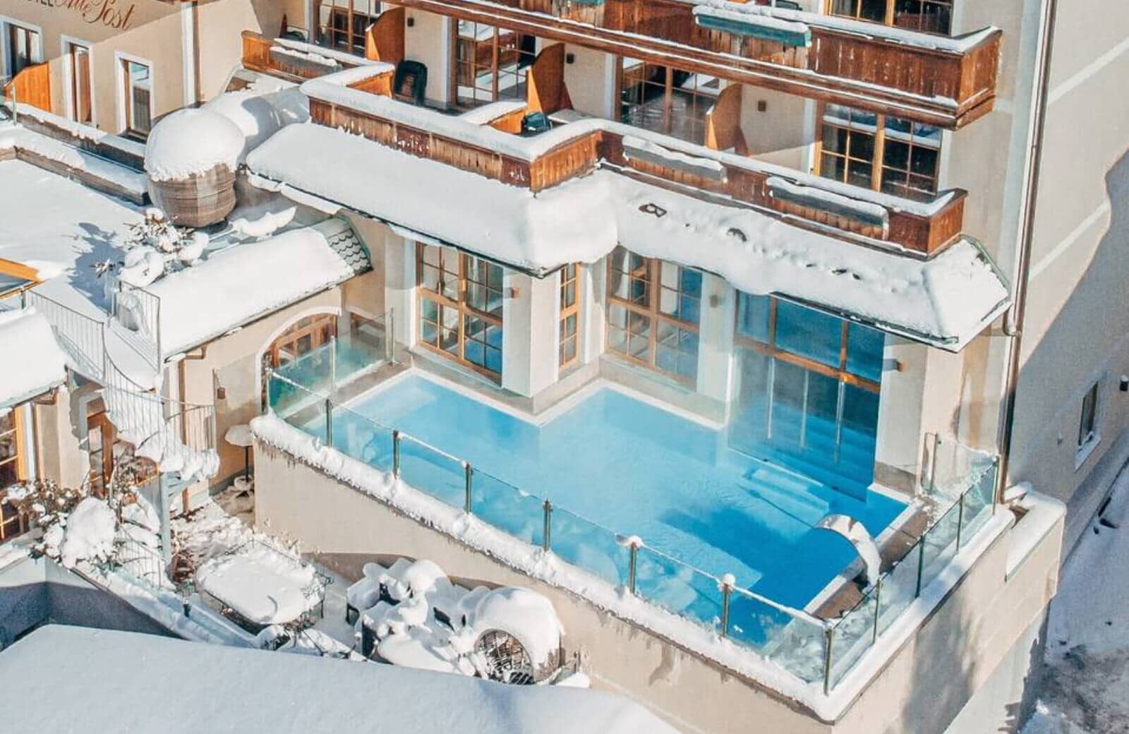 Heated outdoor pool with glass safety railing and mountain architecture