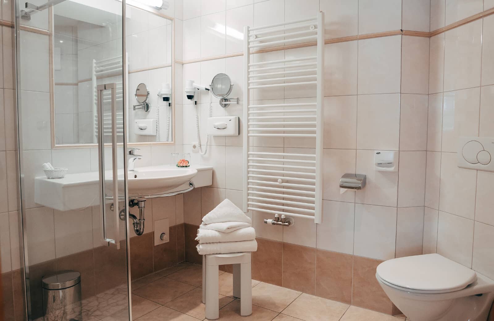 Bathroom with heated towel rail, walk-in shower, and wall-mounted hairdryer