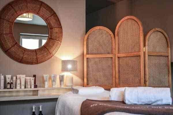 Spa treatment room with massage table and rattan privacy screen