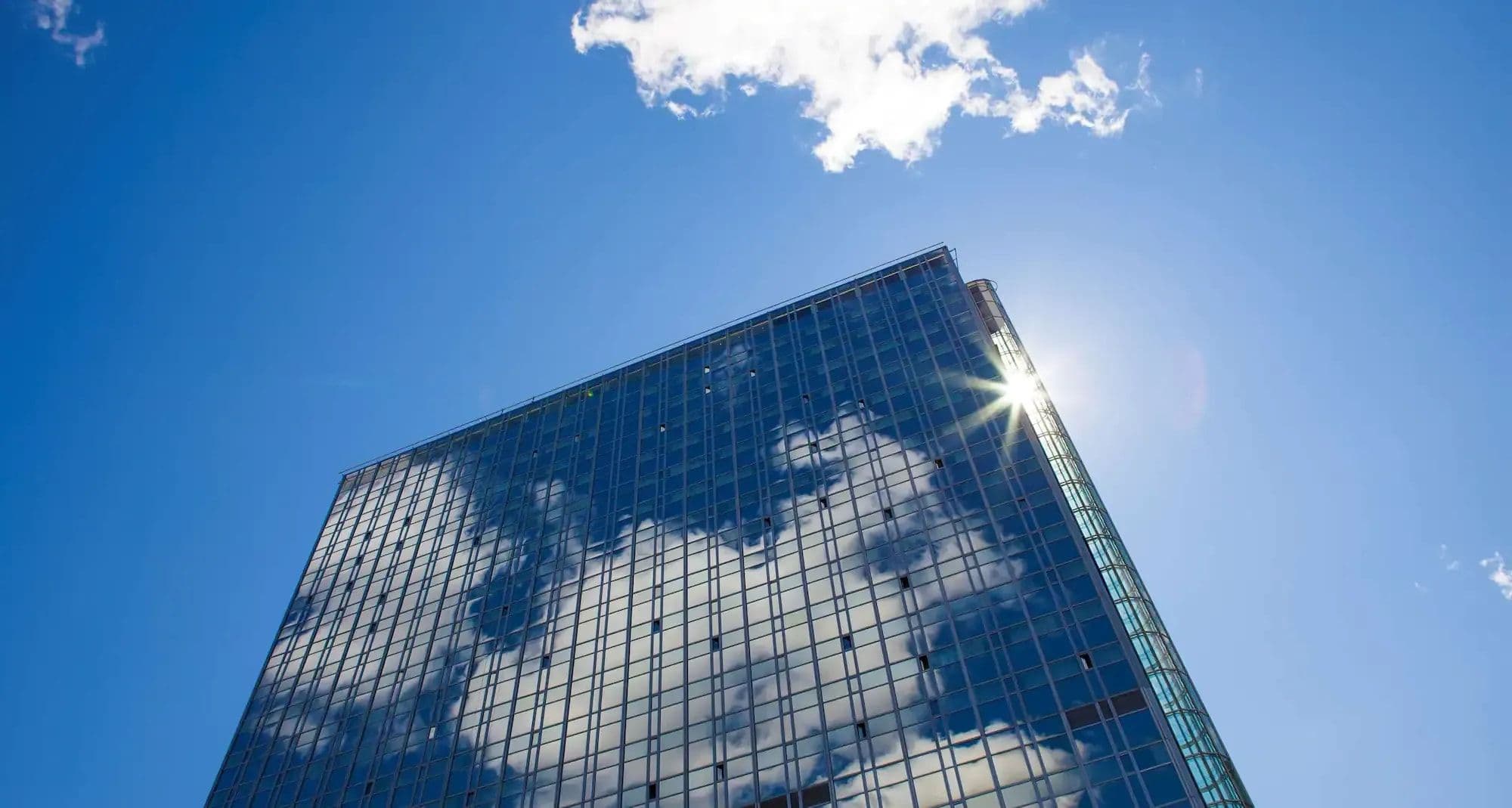 Building exterior with floor-to-ceiling glass windows and cloud reflections