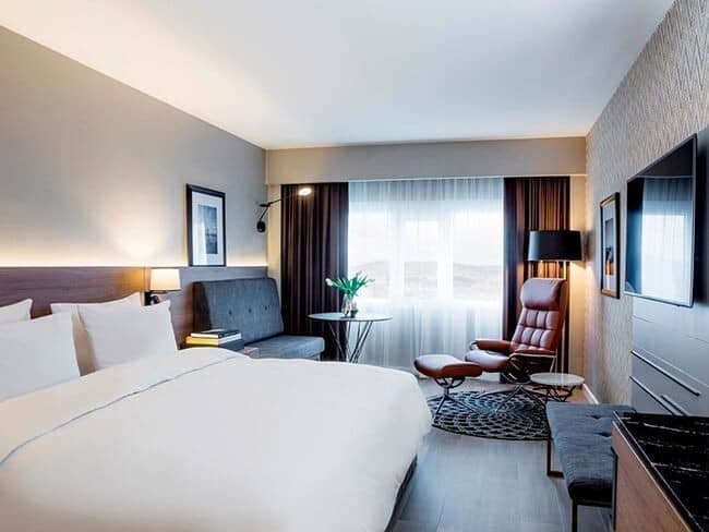 Guest bedroom with king bed and leather armchair seating area