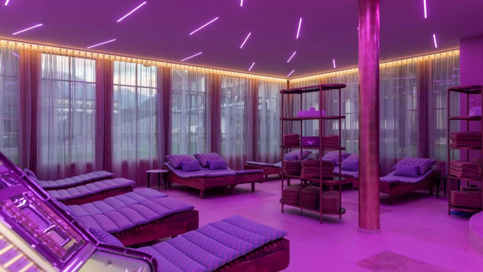 Spa relaxation room with heated daybeds and purple ambient lighting