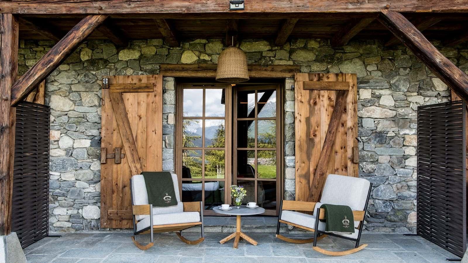 Covered stone patio with rocking chairs and mountain-view glass doors