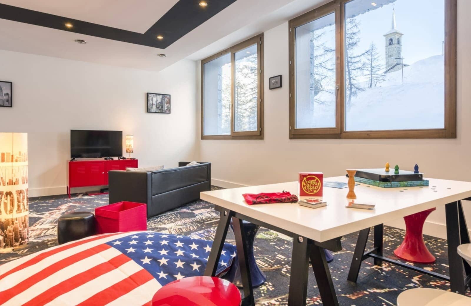 Media room with board games, flat-screen TV, and snow-covered church views