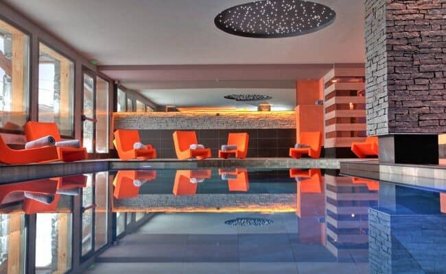 Indoor pool with starlight ceiling feature and poolside lounge chairs