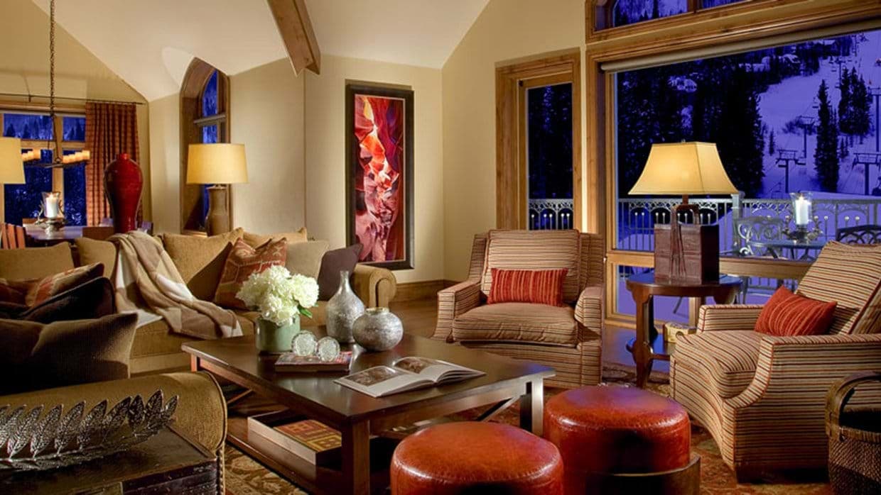 Living area with sofa and armchairs overlooking floodlit night ski slopes