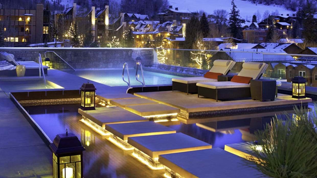 Rooftop pool with lounge seating and snowy village views
