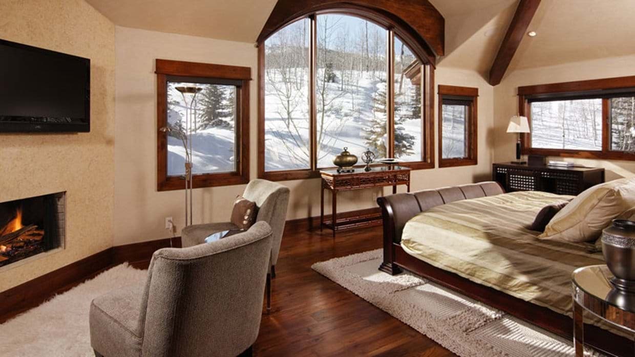 Primary bedroom with gas fireplace and floor-to-ceiling mountain views
