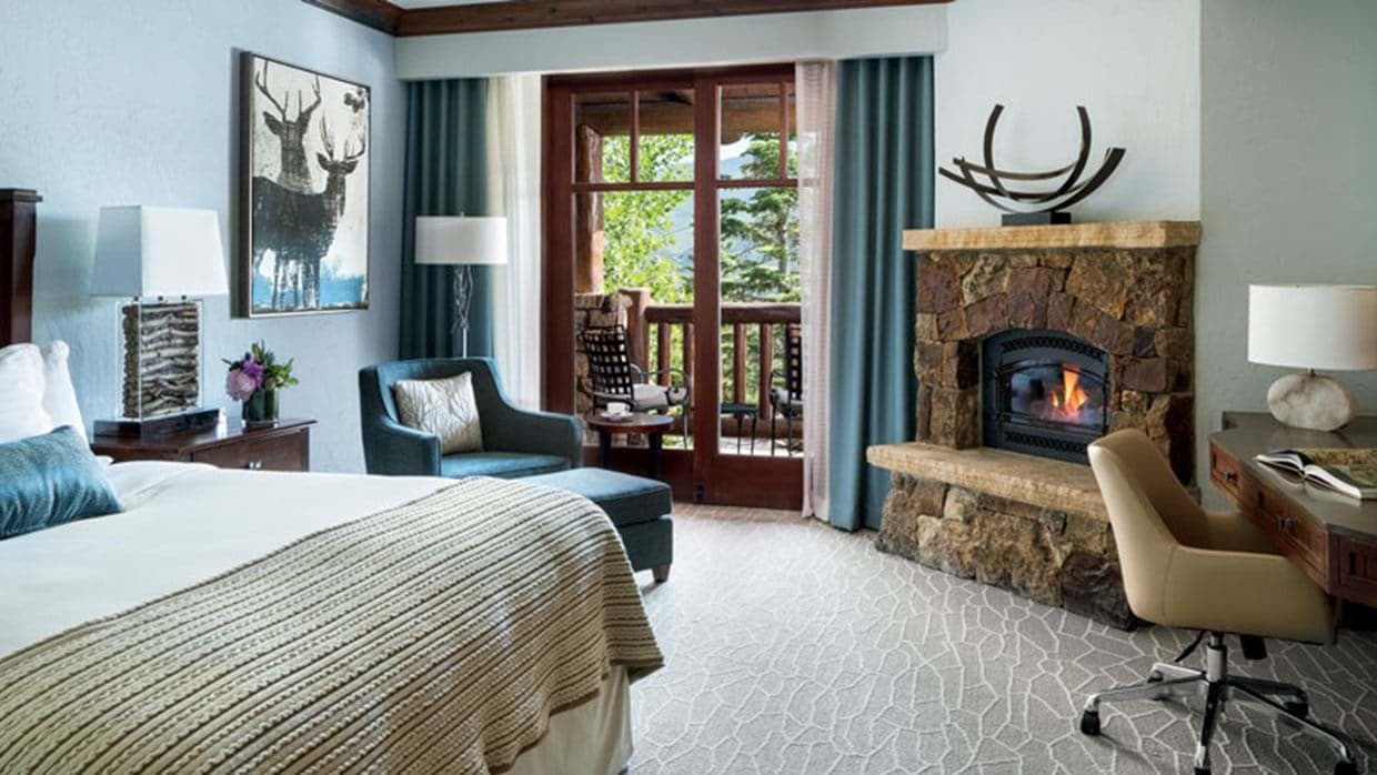 Primary bedroom with stone fireplace, workspace, and private balcony