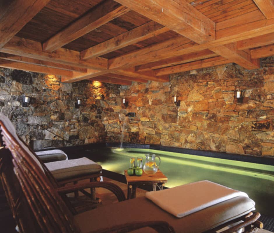 Indoor grotto pool with stone walls and timber-beamed ceiling