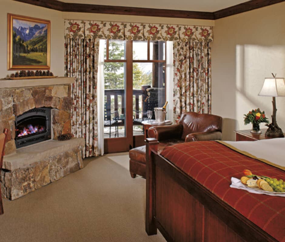 Primary bedroom with stone fireplace and private balcony access