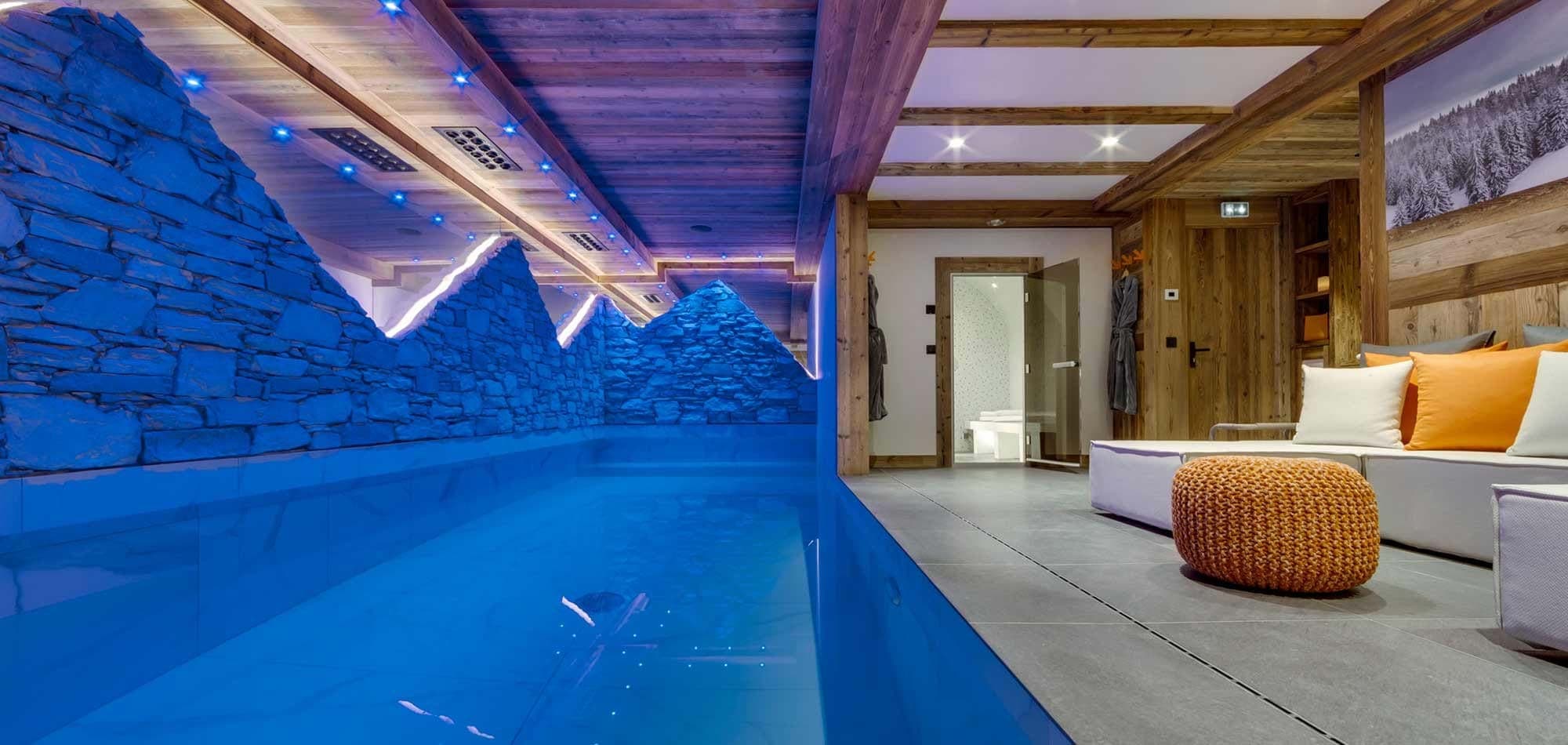Indoor pool area with mountain-silhouette stonework and adjacent steam room