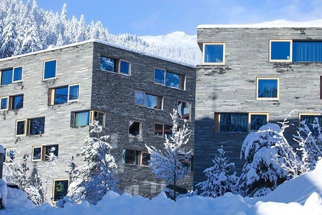 Stone facade apartment exterior with direct mountain views and snowy surroundings