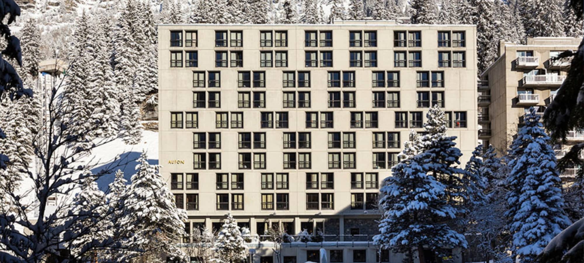 Mid-century brutalist hotel exterior with ski-in/ski-out access and snowy forest surroundings