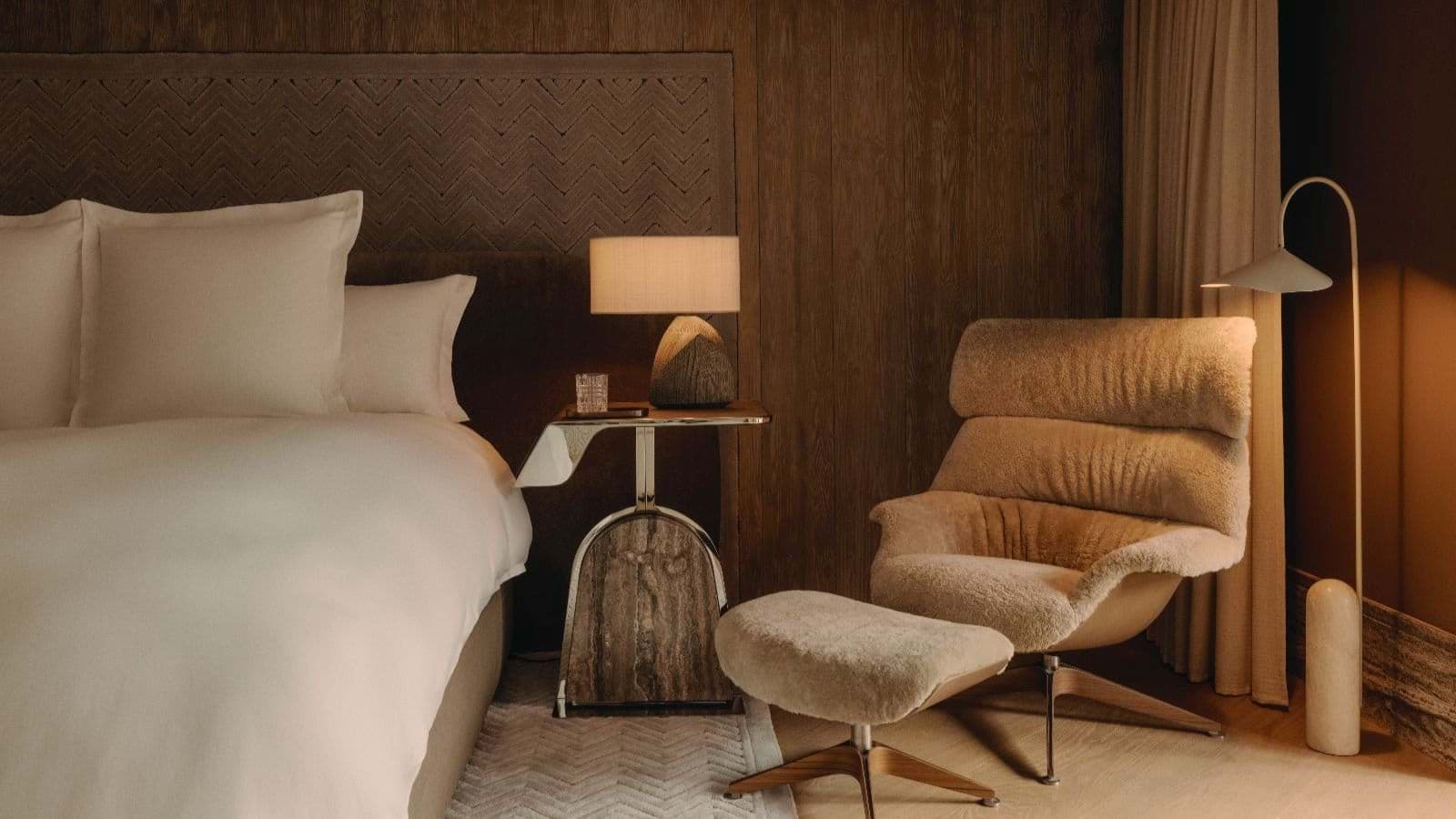 Primary bedroom with reading chair, ottoman, and wood-paneled walls