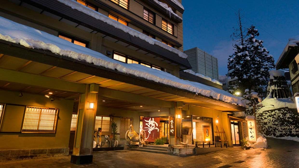Ryokan exterior with wide covered entrance and snow-covered roof