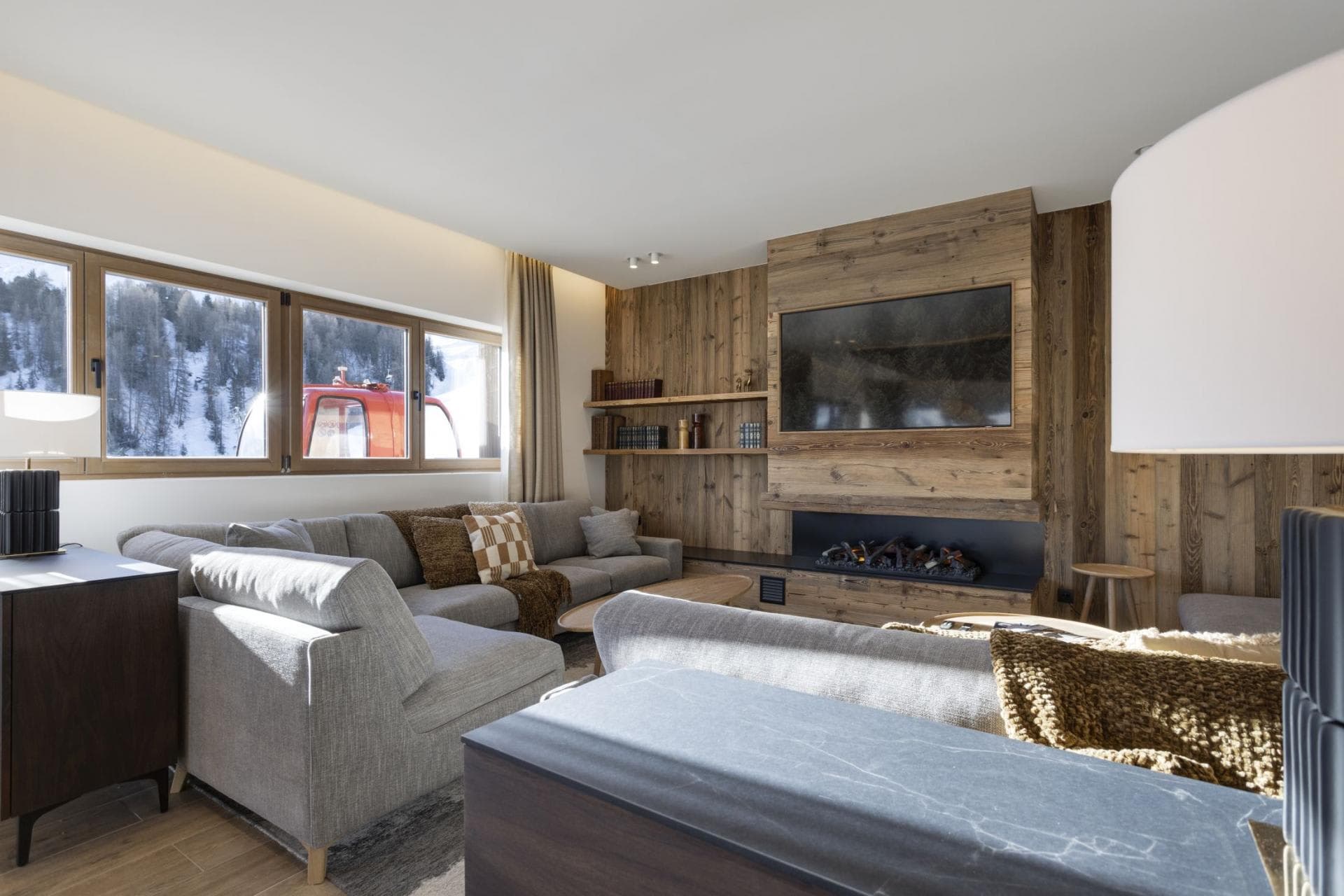 Living area with electric fireplace, wall-mounted TV, and view of ski lift
