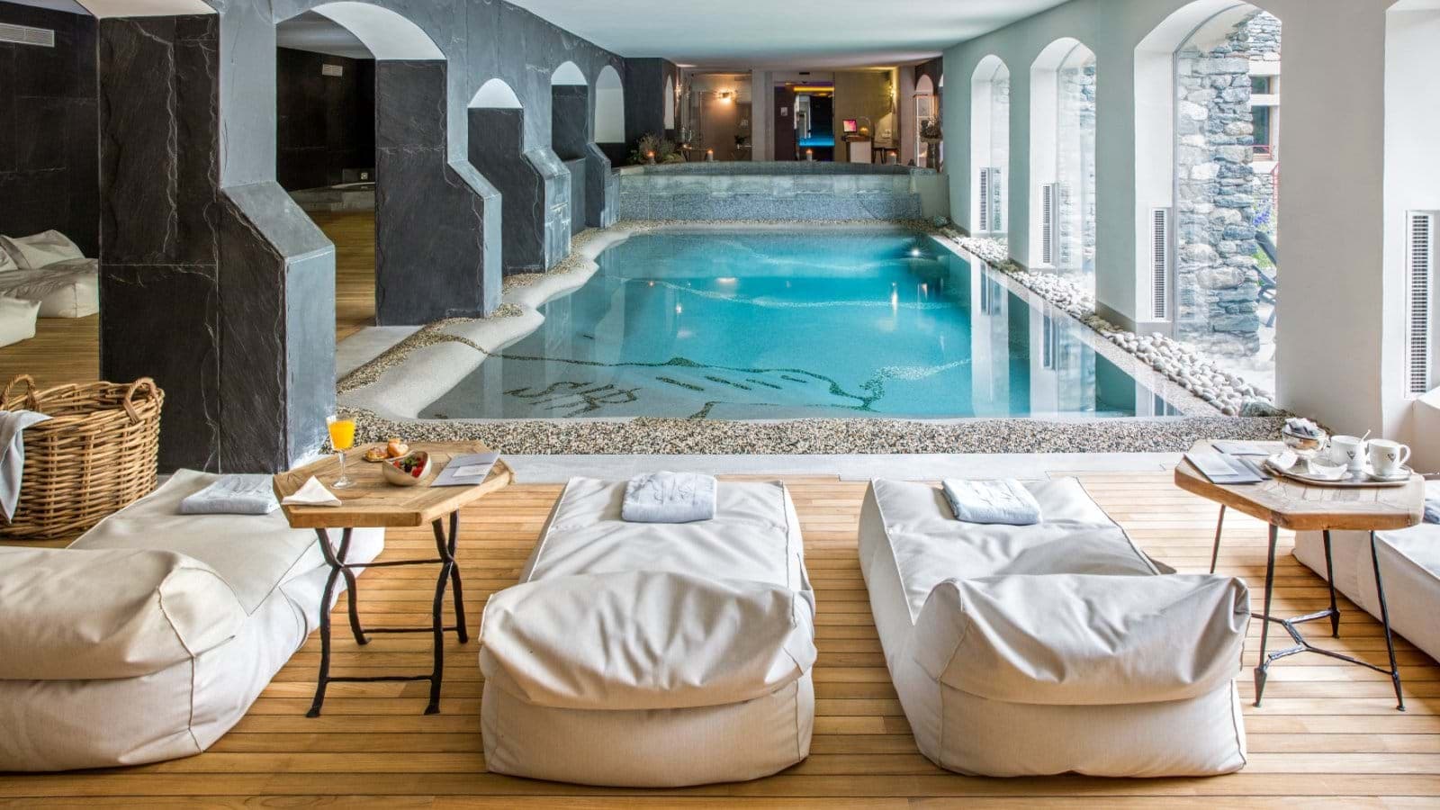 Indoor pool and spa area with heated loungers and garden views