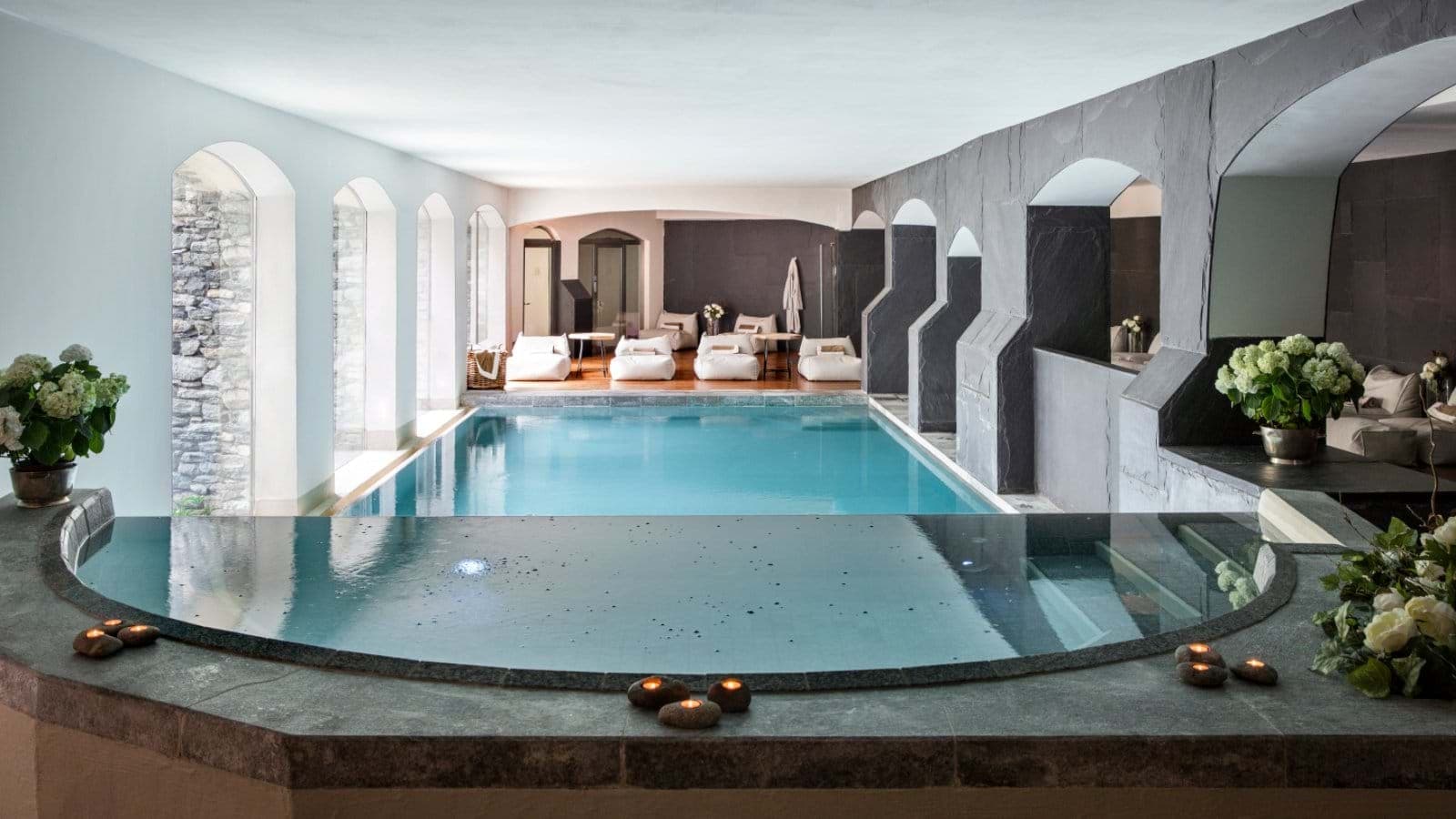 Indoor pool and hot tub with poolside lounge seating