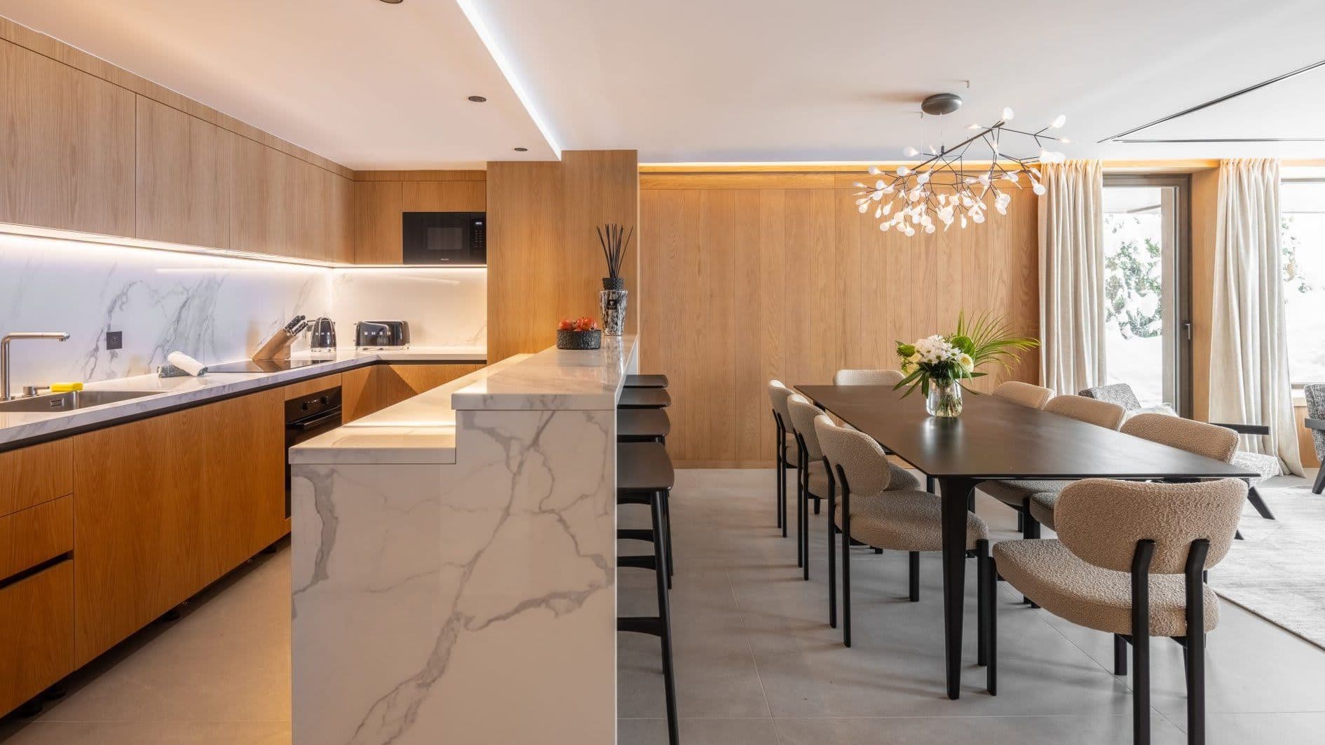 Open-plan kitchen and dining area with marble waterfall island and seating for 8