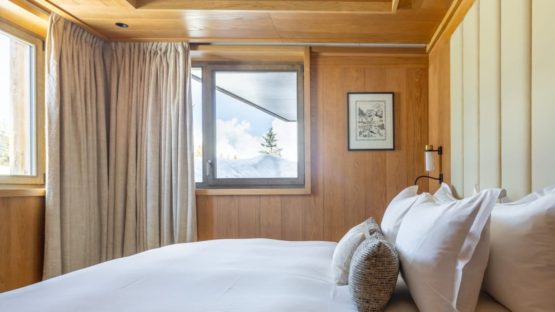 Guest bedroom with oak-paneled walls and snowy mountain views