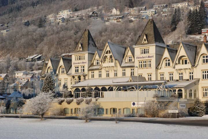 Historic hotel exterior with Swiss-style architecture and mountain hillside backdrop
