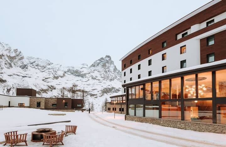 Modern building exterior with outdoor fire pit and snow-covered mountain views