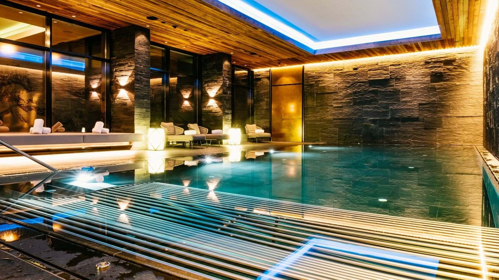 Indoor pool with stone walls and poolside lounge seating