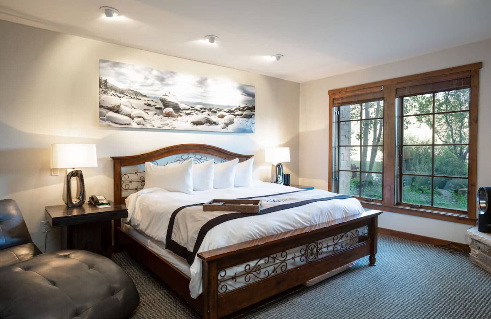 Primary bedroom with king bed, leather chaise, and garden views